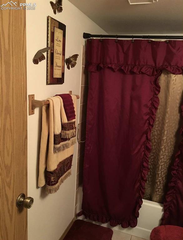 Image 18 of 20: Full bathroom featuring shower / tub combo with curtain and tile patterned 