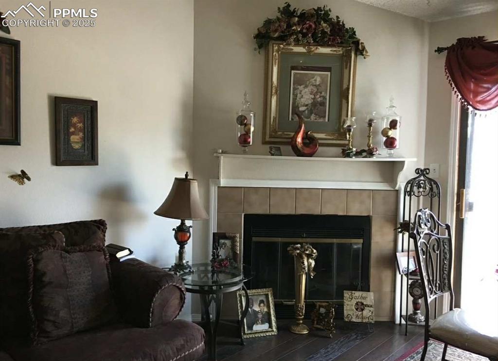 Image 6 of 20: Living area with a tile fireplace and wood-type flooring