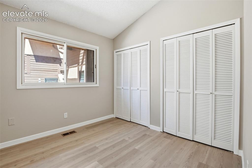 Image 13 of 19: Interior room featuring wood-finish flooring, two sets of louvered bifold c