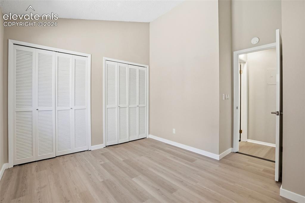 Image 14 of 19: Spacious room featuring wood-finish flooring, neutral-toned walls, and a va