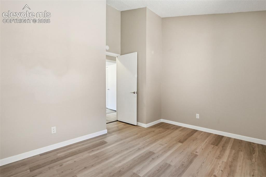 Image 15 of 19: Spacious room featuring wood-finish flooring, light neutral wall tones, and