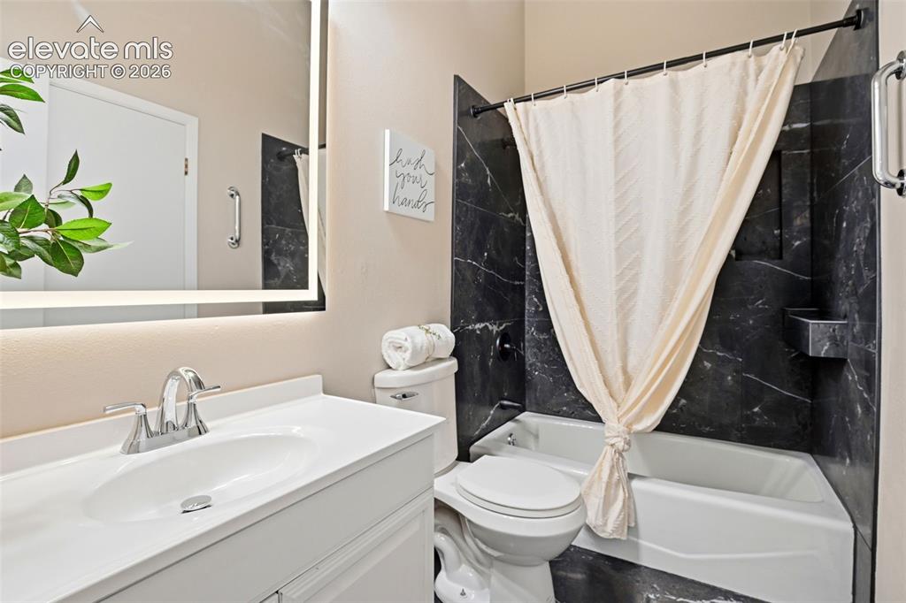 Image 16 of 19: Bathroom with a vanity featuring an integrated sink and chrome faucet, an i