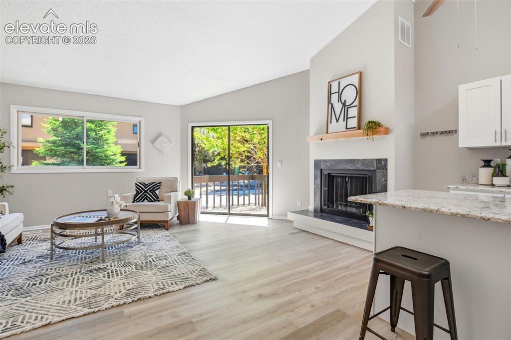 Image 3 of 19: Vaulted ceiling living area featuring light wood-finish flooring, a black s