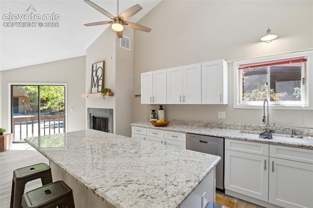 Image 7 of 19: Kitchen featuring a large island with stone countertops, white shaker cabin