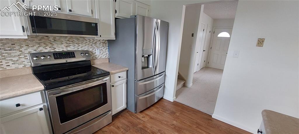 Image 18 of 46: Kitchen with stainless steel finishes, light countertops, tasteful backspla