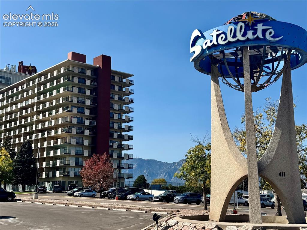 Caption: High-rise building with multiple balconies, a mountain range in the background, and a prominent "Sat