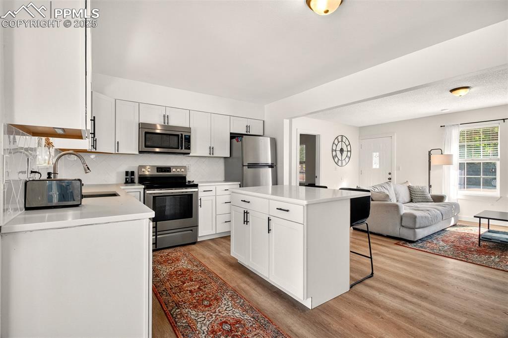 Image 6 of 29: GORGEOUS kitchen with quartz counters, kitchen island, herringbone backspla