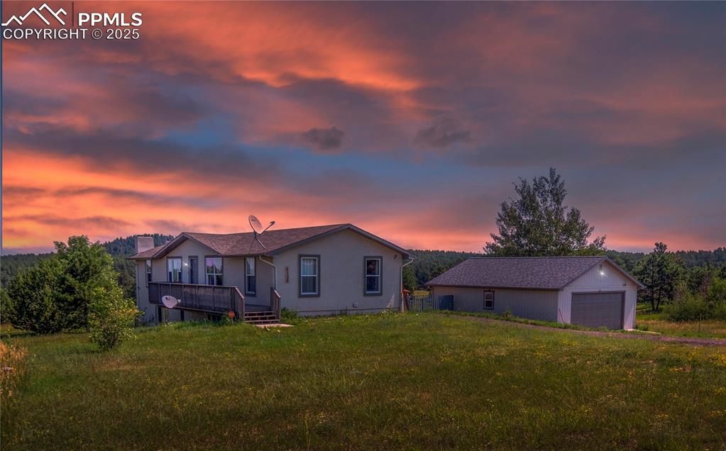 Caption: View of front of property with a detached garage, a front lawn, an outbuilding, and a deck