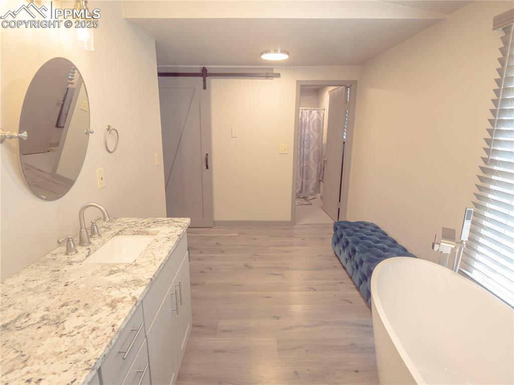 Image 13 of 39: Full bathroom with wood finished floors, vanity, and a freestanding bath