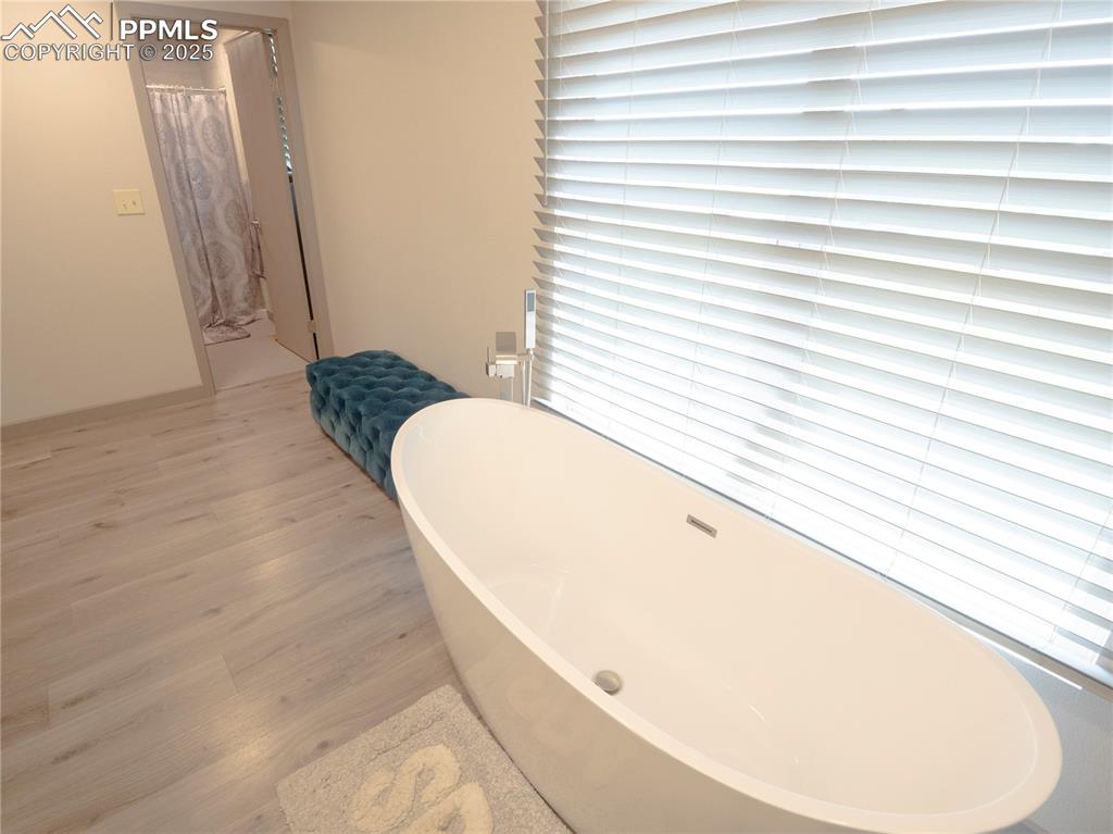 Image 15 of 39: Full bathroom with wood finished floors and a soaking tub