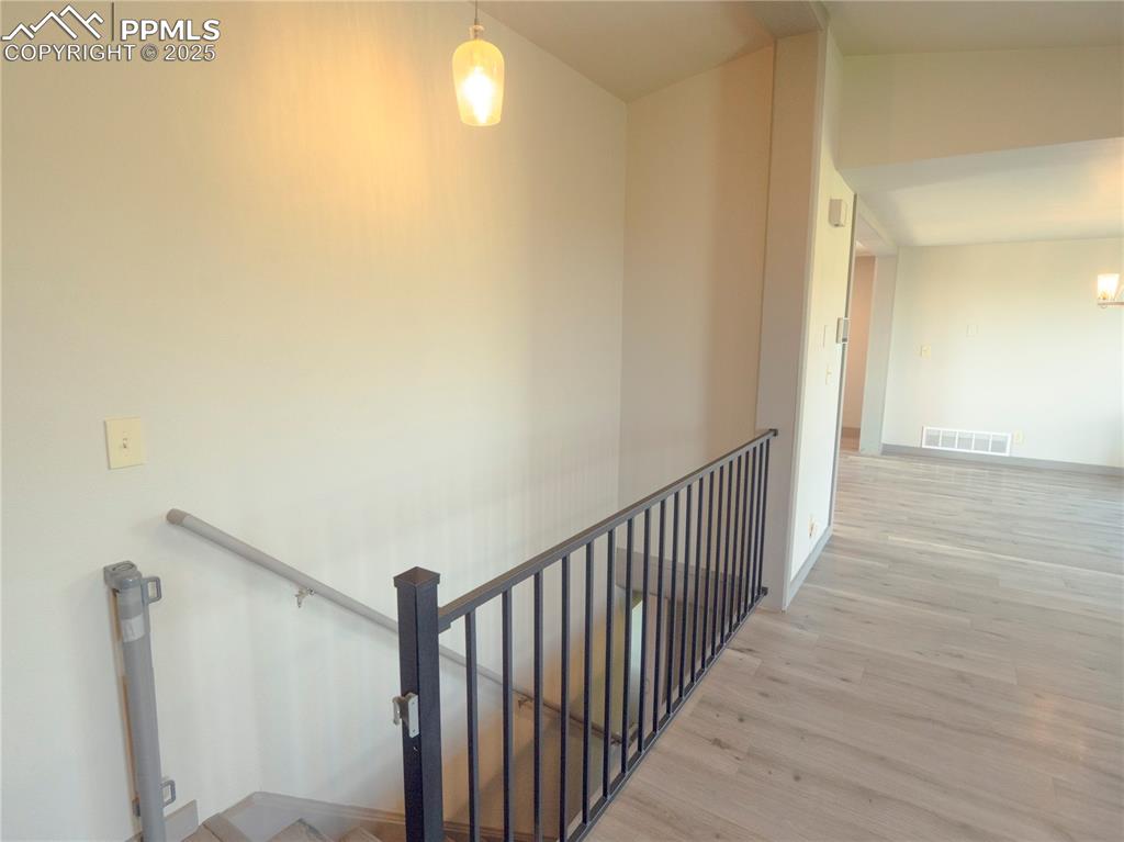 Image 17 of 39: Hallway featuring an upstairs landing and wood finished floors