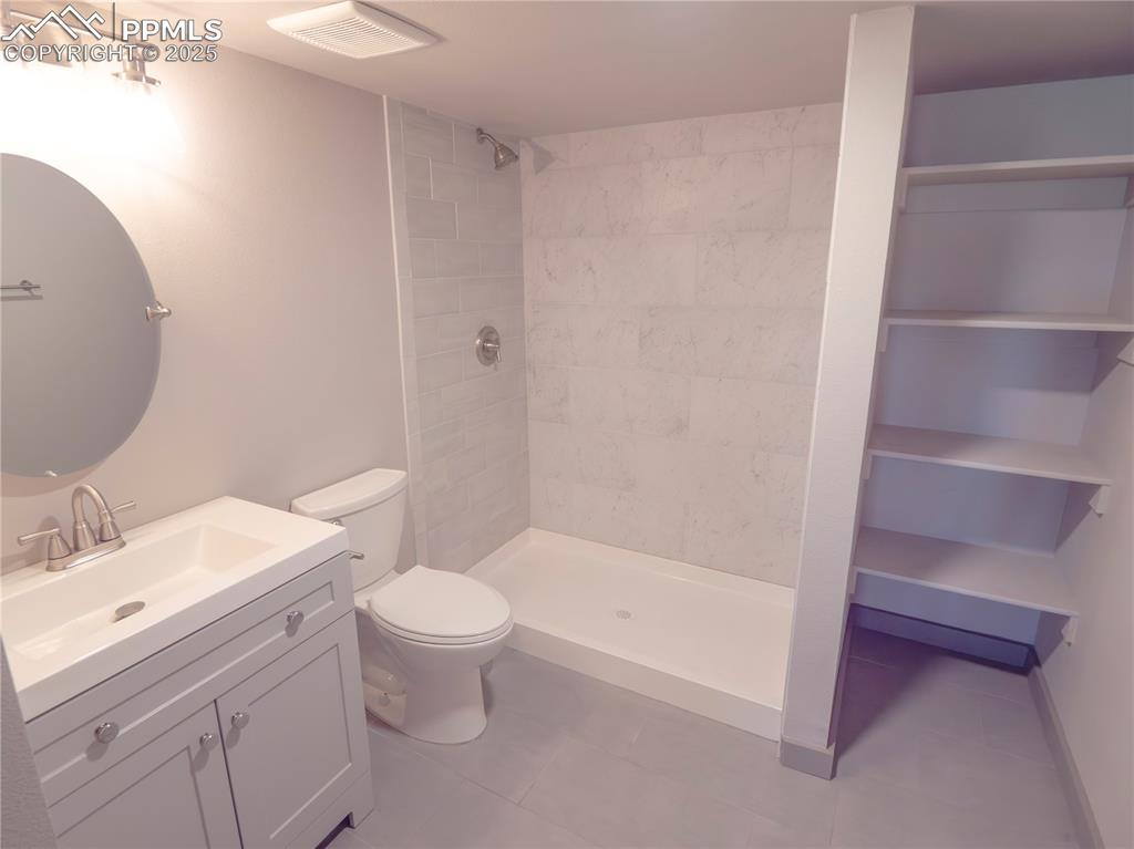 Image 26 of 39: Bathroom featuring vanity, a tile shower, and tile patterned floors