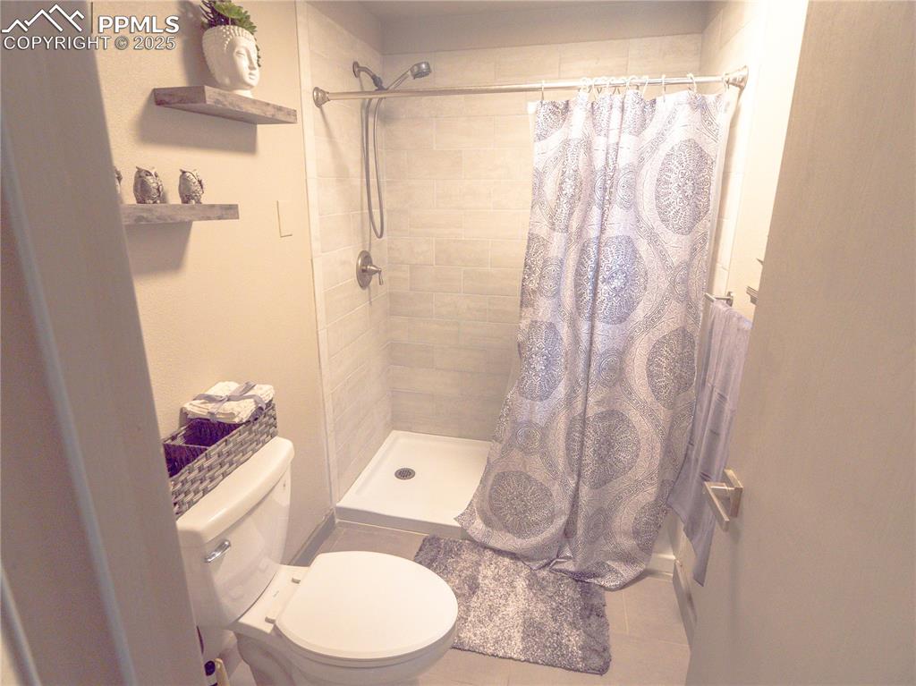 Image 27 of 39: Bathroom featuring tiled shower and toilet