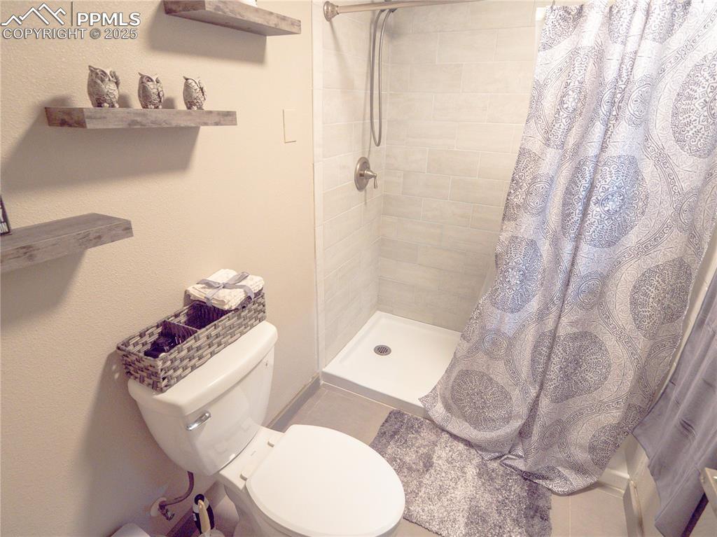 Image 28 of 39: Full bath featuring tiled shower and toilet