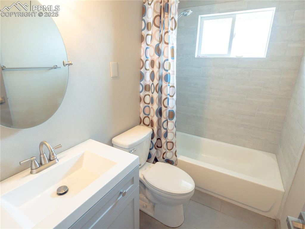 Image 30 of 39: Bathroom featuring vanity, shower / bathtub combination with curtain, and t