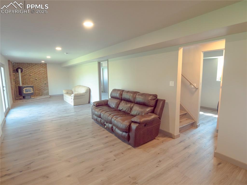 Image 32 of 39: Living room with a wood stove, light wood-style flooring, stairway, and rec