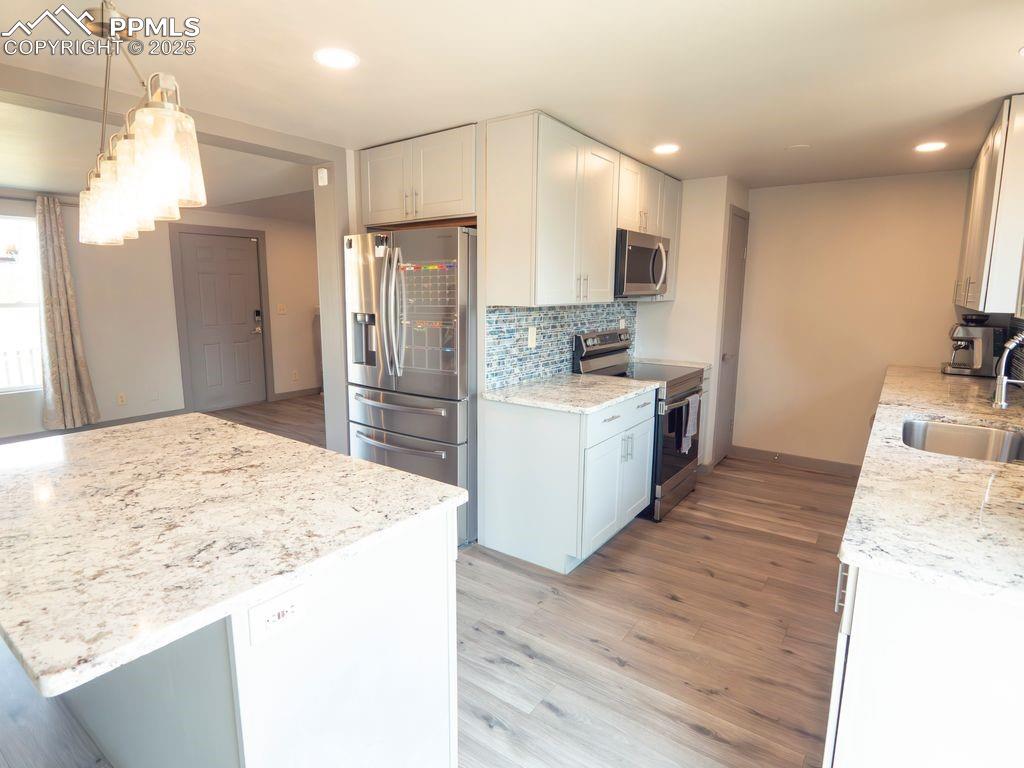 Image 8 of 39: Kitchen featuring light wood-style floors, appliances with stainless steel 