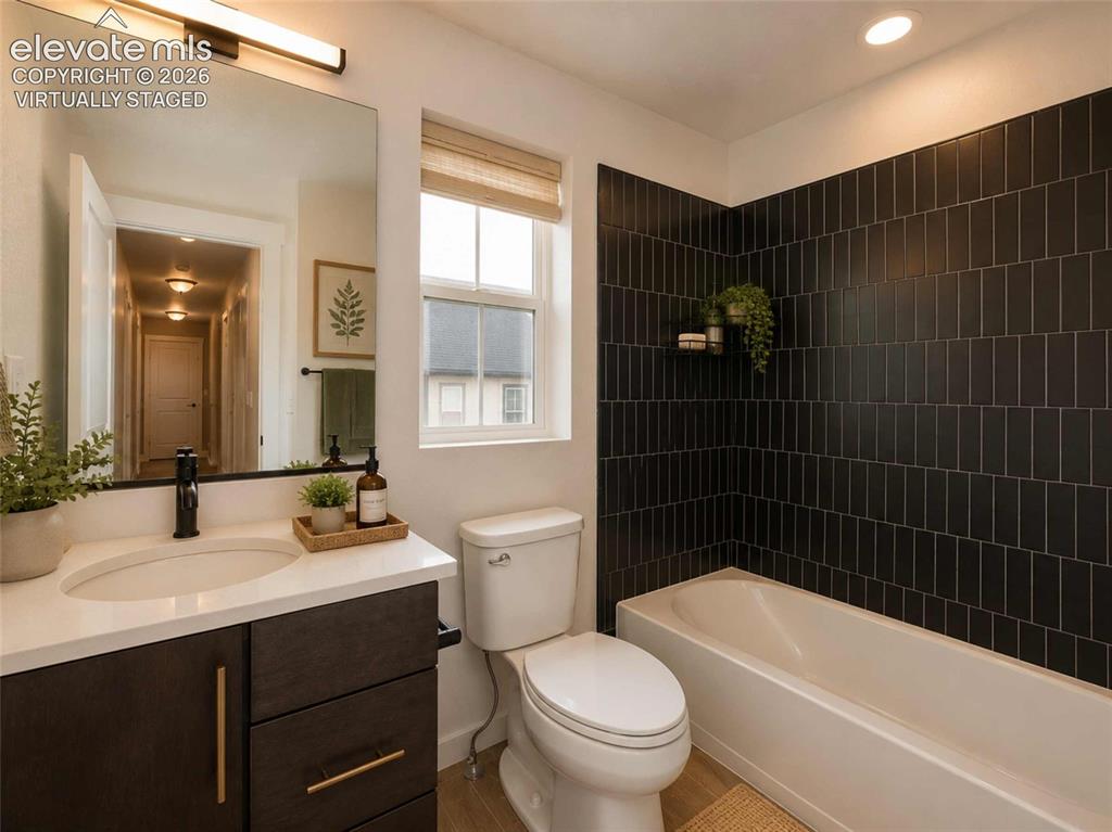 Image 10 of 40: Bathroom featuring a dark subway tile shower surround, a white bathtub, and
