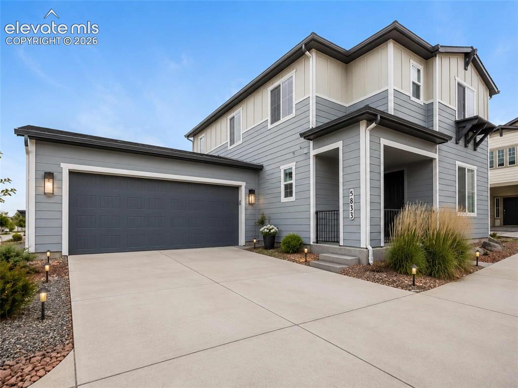 Image 12 of 40: Modern two-story residence with a gray and cream exterior siding, a two-car
