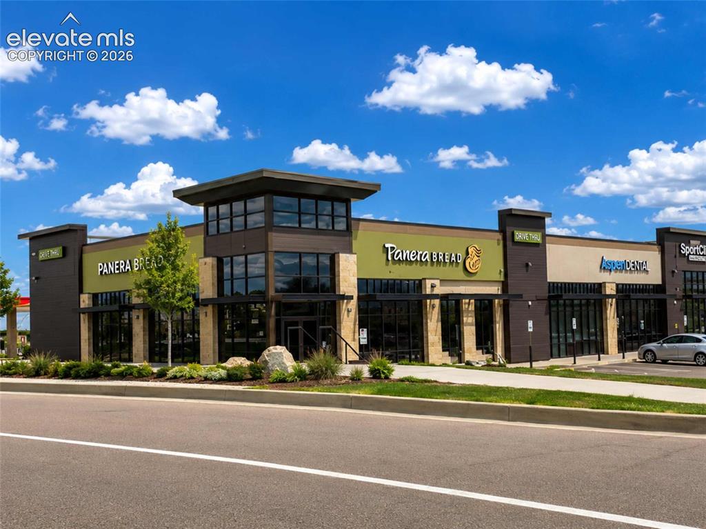 Image 19 of 40: Modern commercial building featuring multiple storefronts, a prominent two-