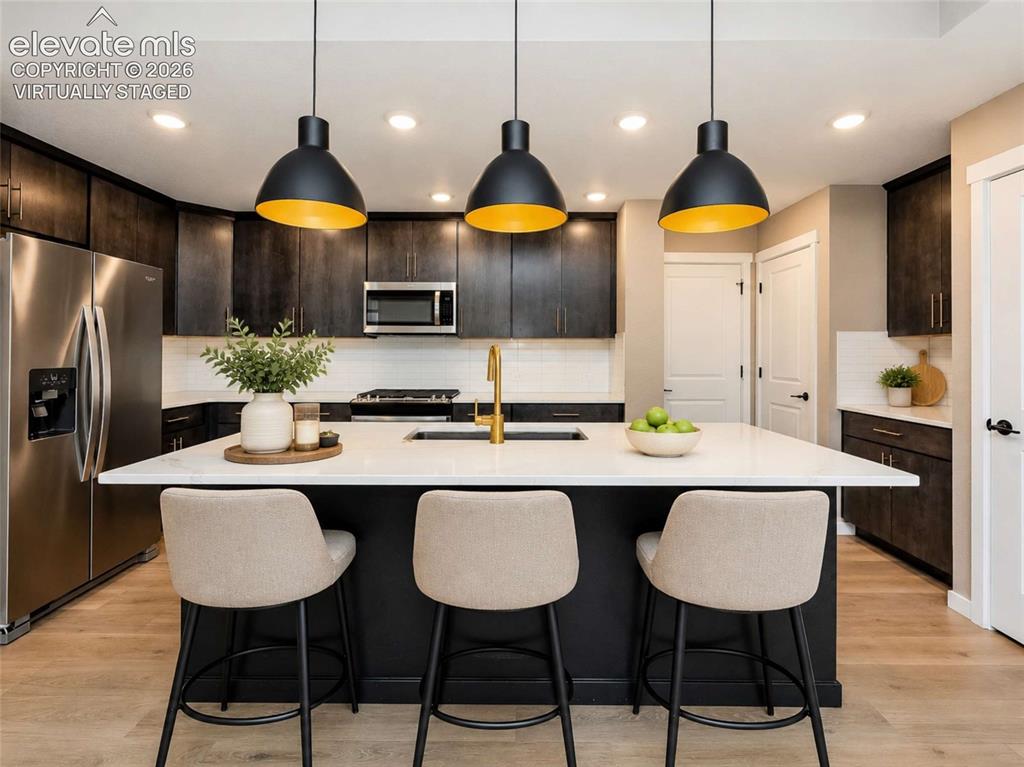 Image 2 of 40: Modern kitchen featuring dark wood-finish
cabinetry, a white countertop i
