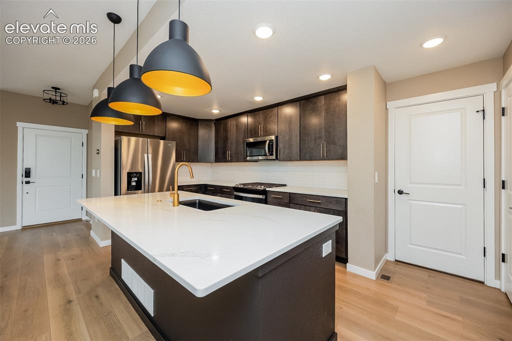 Image 27 of 40: Modern kitchen featuring a large island with a white countertop and undermo
