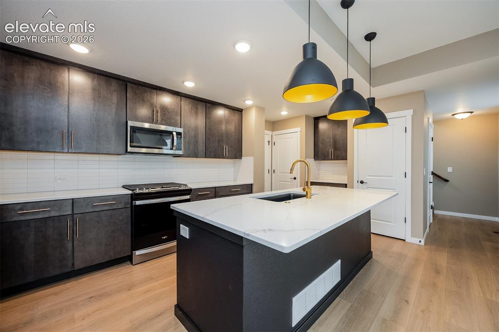 Image 28 of 40: Contemporary kitchen featuring a large island with a quartz countertop, gol