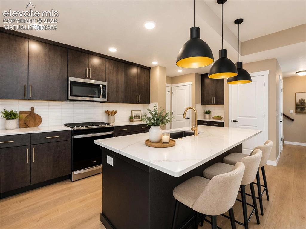Image 3 of 40: Kitchen featuring a large island with a white countertop, dark wood-finish