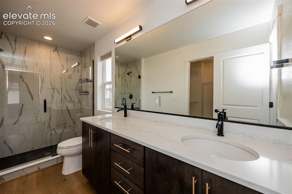 Image 32 of 40: Bathroom featuring a dual vanity with dark wood-finish cabinetry, white cou
