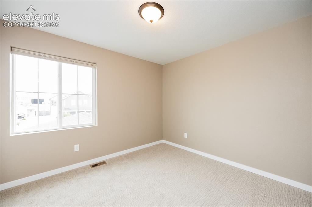 Image 33 of 40: Room with neutral tone walls, white trim, and light-colored carpet flooring