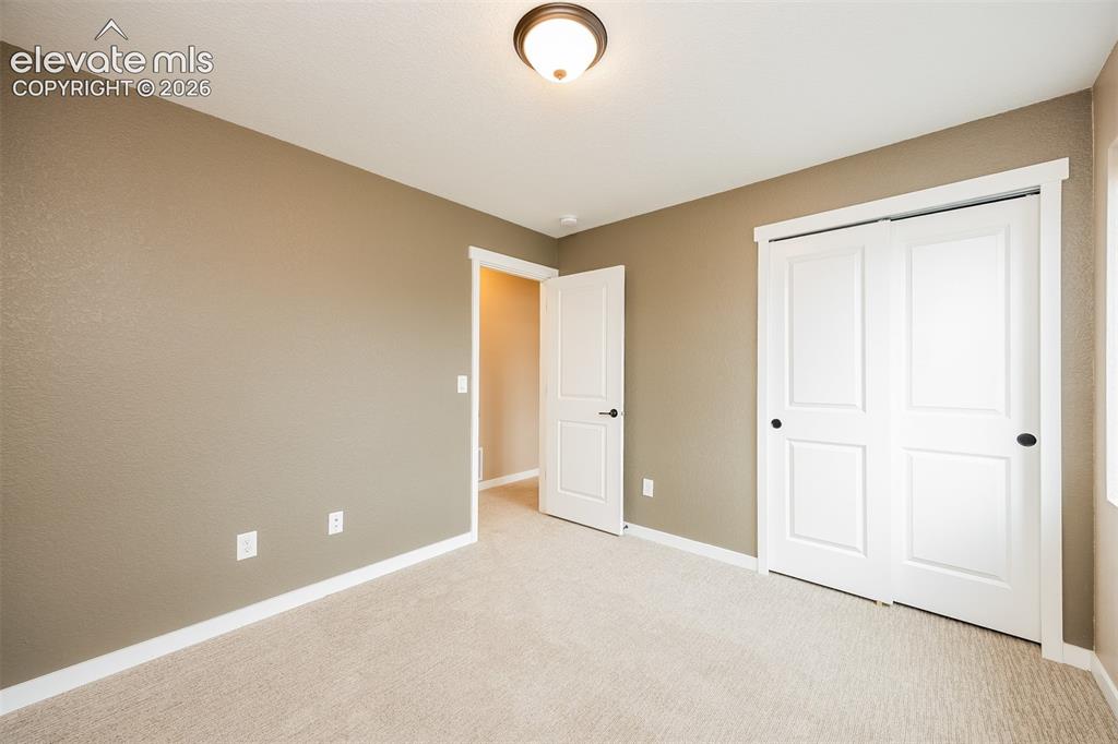 Image 34 of 40: Neutral-toned room featuring light-colored carpeting, white trim, and a cei