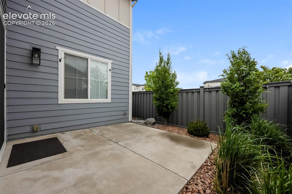 Image 39 of 40: Private concrete patio with a gray horizontal plank siding exterior
