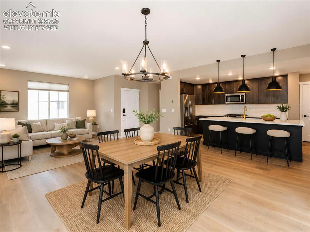 Image 5 of 40: Open-concept living space featuring wood-finish flooring, a contemporary ki