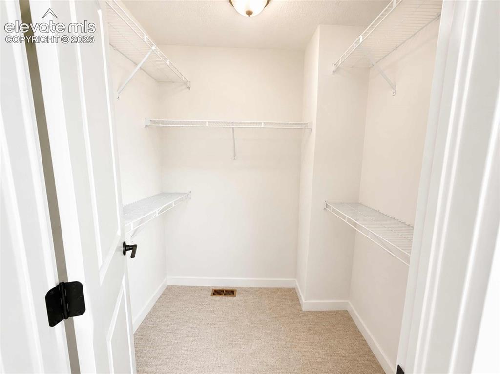 Image 7 of 40: Walk-in closet featuring light-toned carpeting, white wire shelving, and a