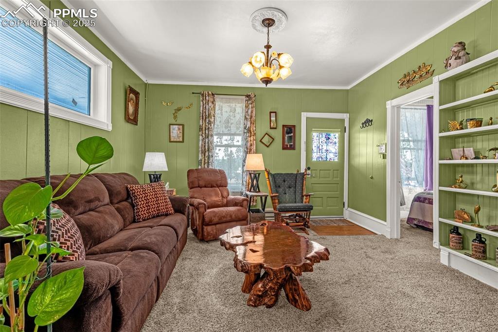 Image 6 of 30: Carpeted living area with a chandelier and crown molding