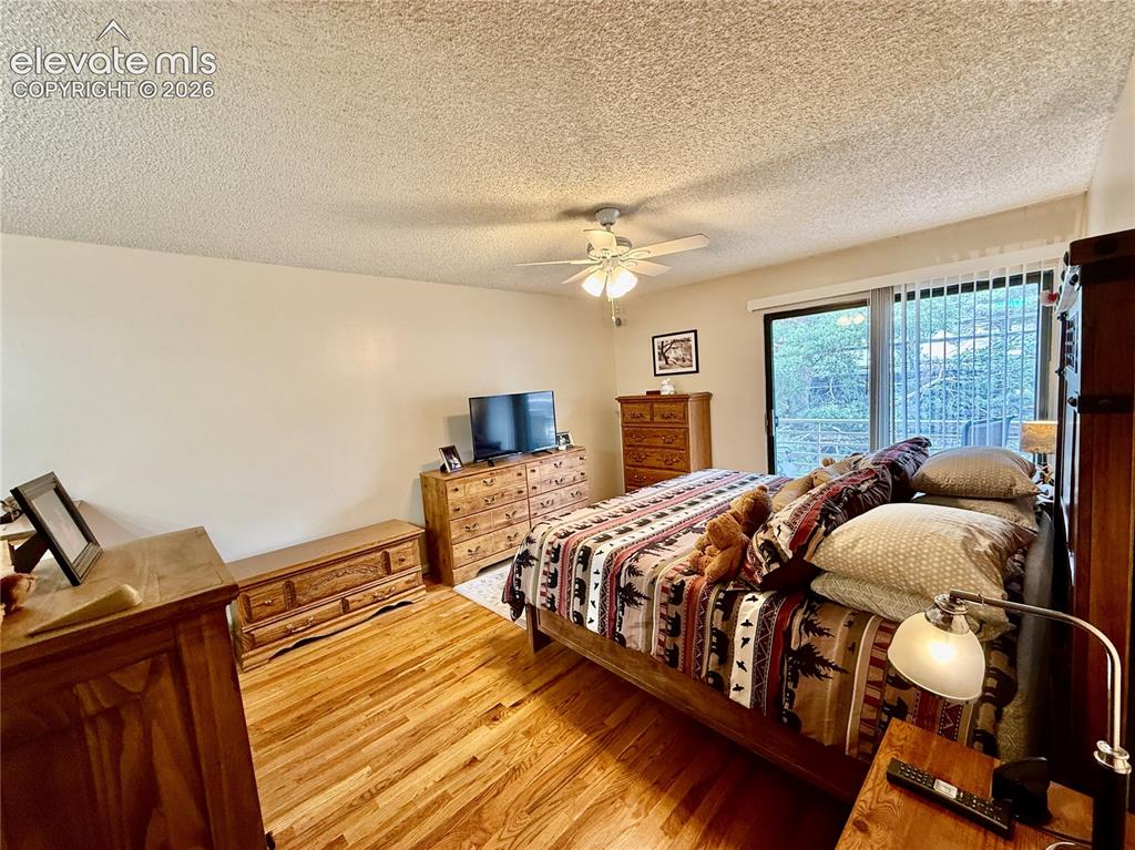 Image 12 of 26: Bedroom featuring wood finished floors, a textured ceiling, and ceiling fan