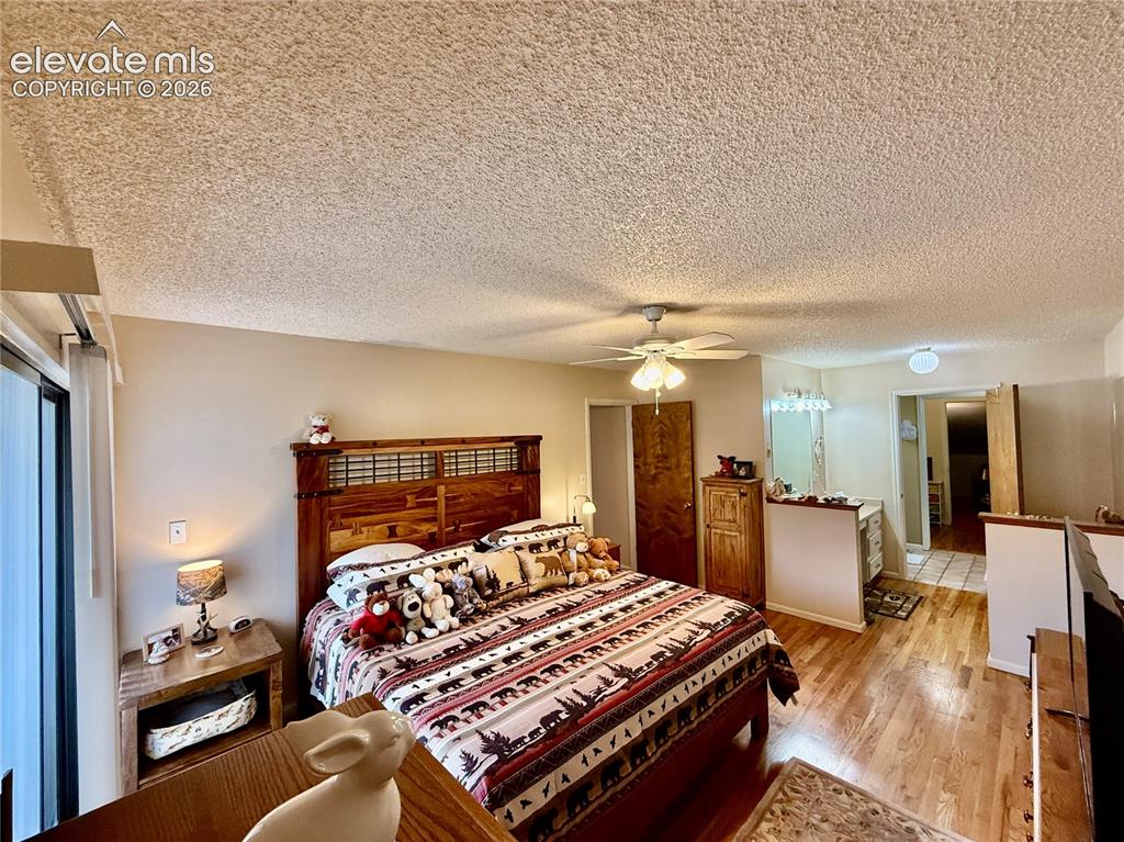 Image 13 of 26: Bedroom with light wood flooring, a closet, ceiling fan, and a textured cei