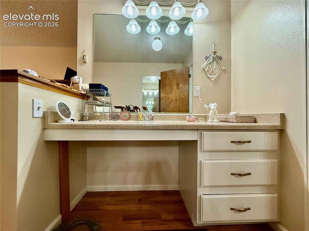 Image 15 of 26: Vanity featuring wood finished floors, and textured ceiling