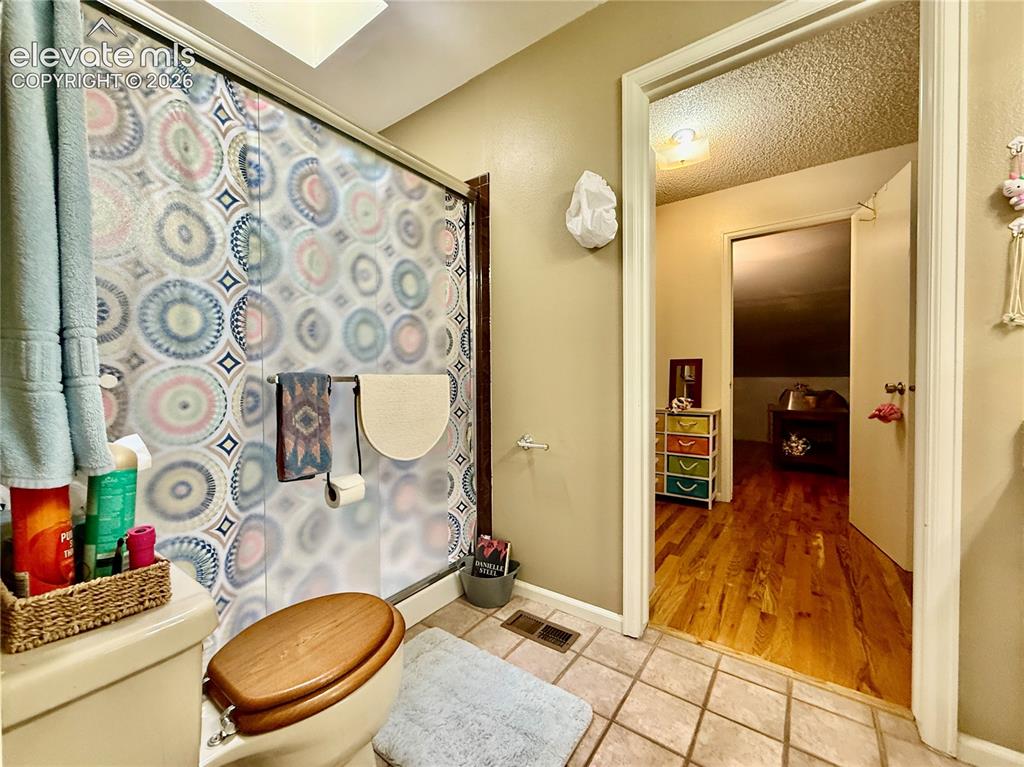 Image 16 of 26: Full bathroom featuring toilet, tile patterned flooring, a shower with curt