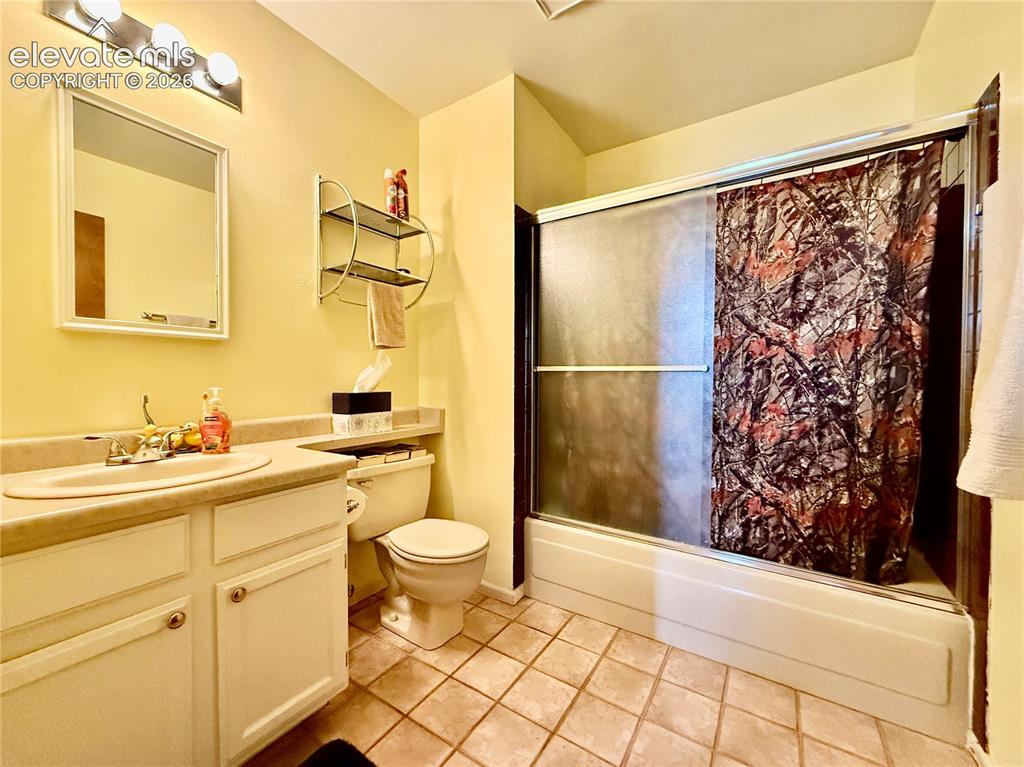 Image 18 of 26: Full bath with toilet, vanity, tile patterned flooring, and combined bath /
