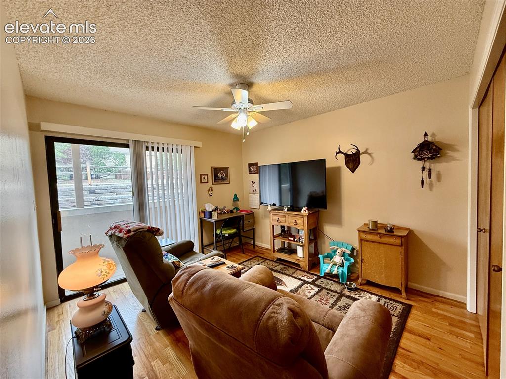 Image 19 of 26: Living area with ceiling fan, a textured ceiling, wood finished floors, and