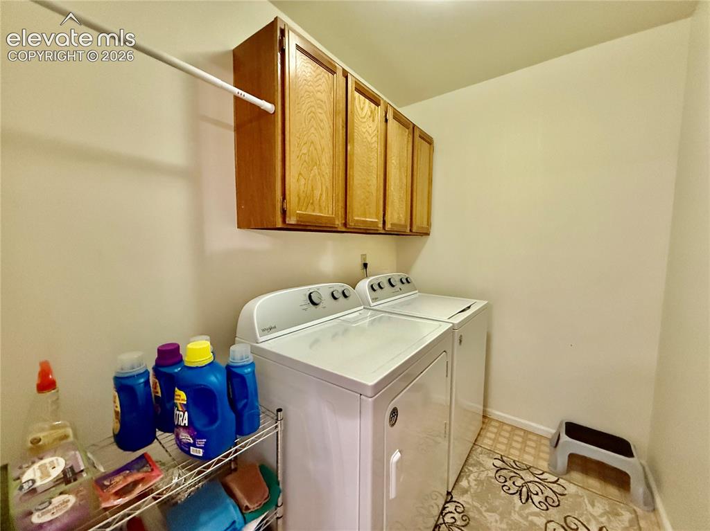 Image 21 of 26: Laundry room featuring independent washer and dryer, cabinet space, and bas