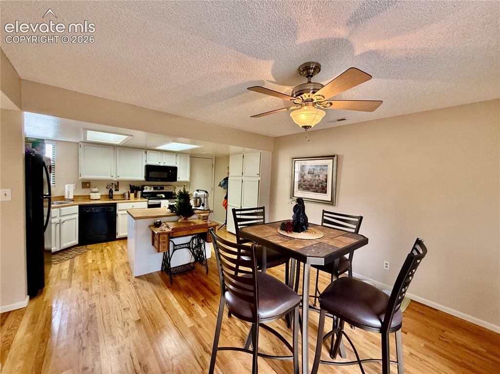 Image 5 of 26: Dining space featuring light wood-style flooring, a textured ceiling, baseb