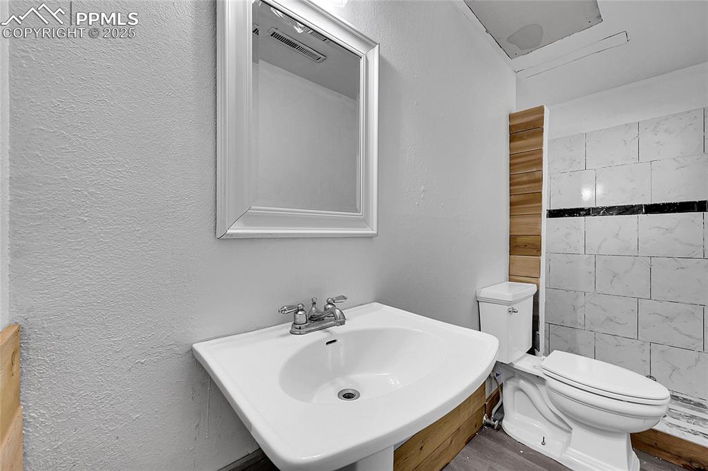 Image 14 of 36: Full bathroom with a textured wall and wood finished floors