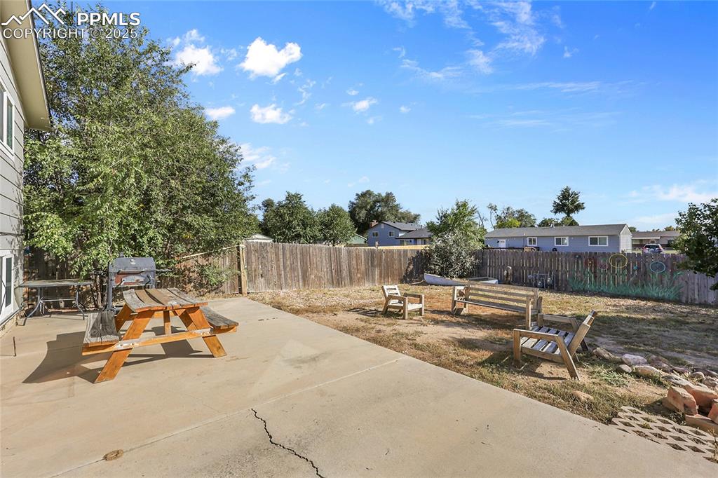 Image 21 of 36: Fenced backyard with a patio area and a grill