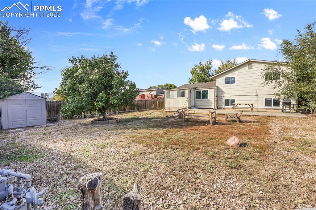 Image 22 of 36: Fenced backyard featuring a storage shed and a patio area
