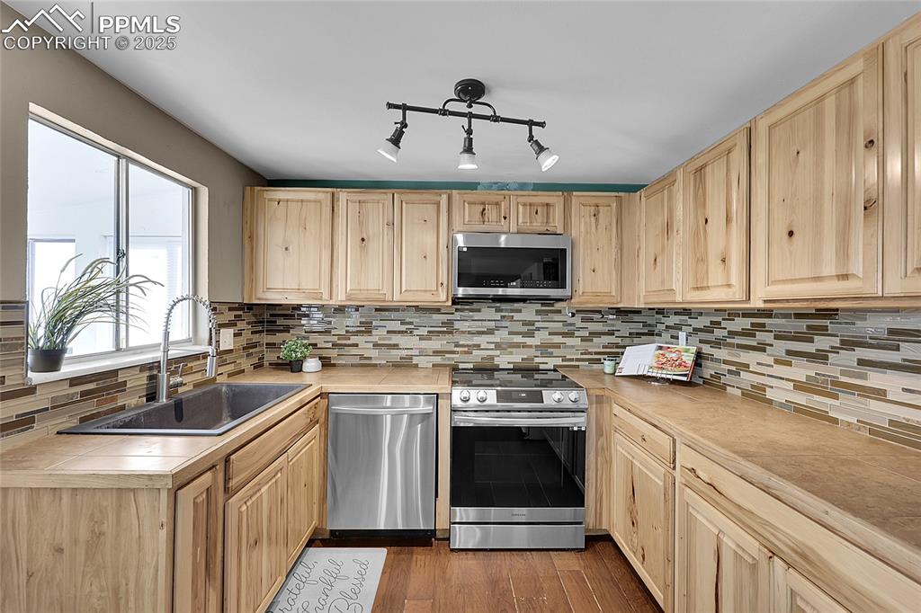 Image 3 of 36: Kitchen featuring stainless steel appliances, light brown cabinetry, tile c