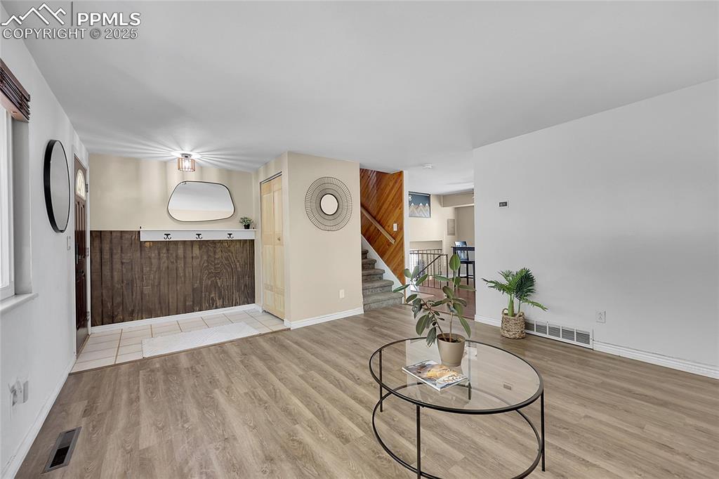 Image 7 of 36: Living area featuring light wood-style flooring, wooden walls, and stairs
