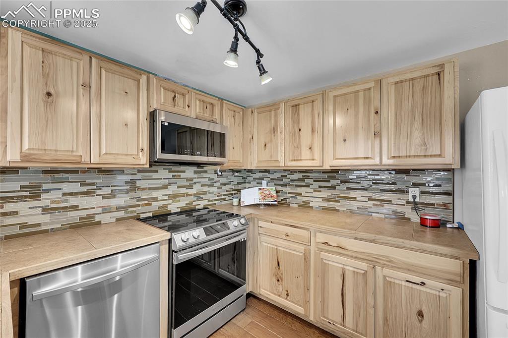 Image 9 of 36: Kitchen with appliances with stainless steel finishes, light wood-type floo