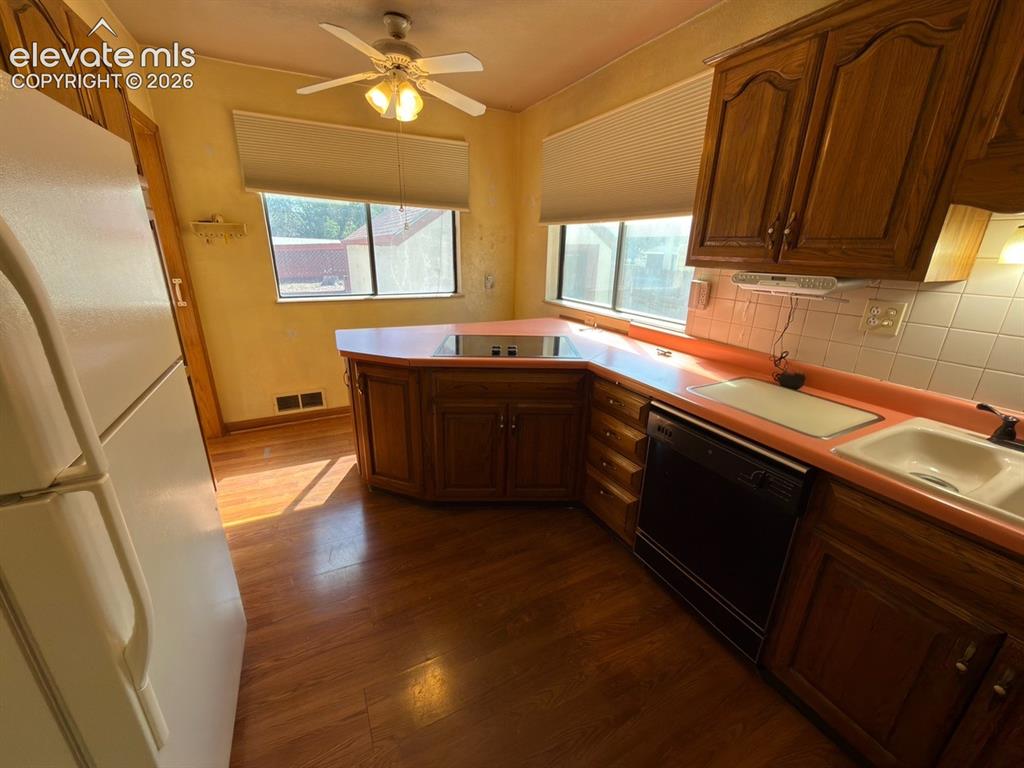 Image 31 of 48: Kitchen featuring wood-finish flooring, two windows with blinds, a ceiling 